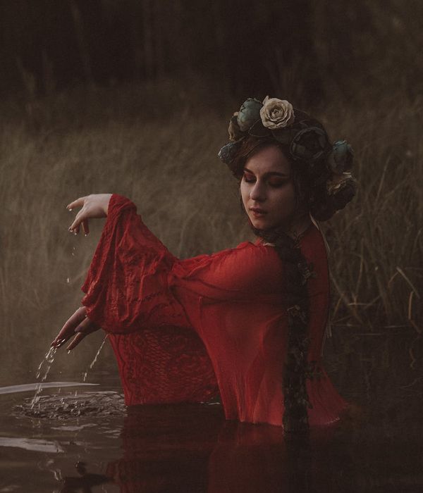 Woman in a calm, flowing pose against a dark background.